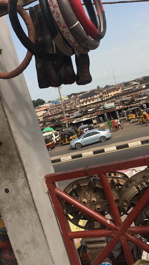 Hanging steering wheel covers over busy street market.