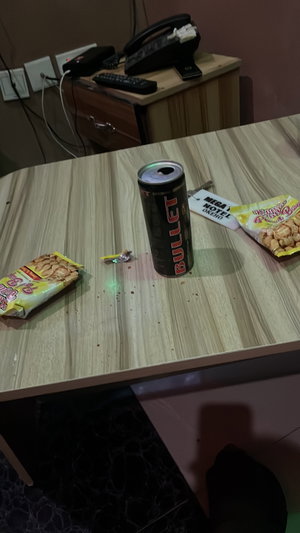 Hotel table with energy drink, snacks, keycard.