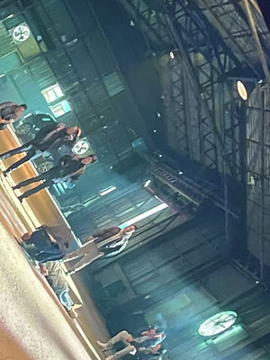 Group of men in dark clothing inside industrial warehouse at night.