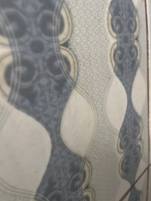 Close-up of patterned tile with blue and beige swirls and dots.