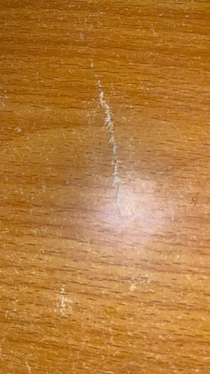 Close-up of a wooden surface with visible grain and minor scratches.