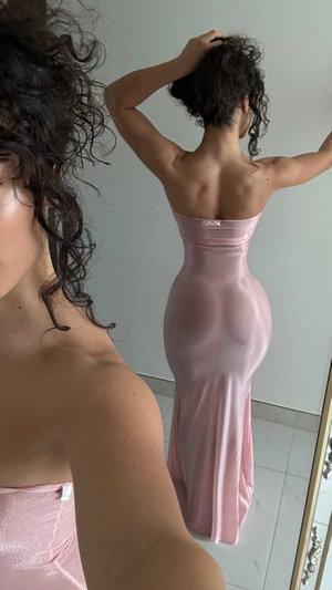 Woman in pink strapless dress, curly hair, mirror selfie, indoor setting.