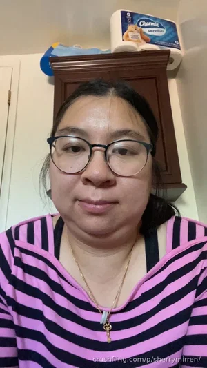 Woman with glasses in pink and black striped shirt, indoors, facing camera.