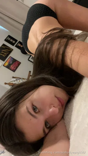 Woman with dark hair in black polka-dot top lying on bed, indoor setting.