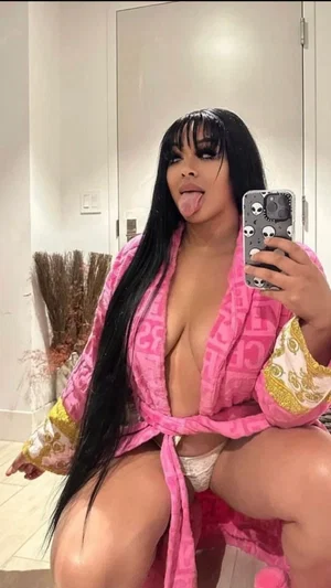 Woman with long black hair in pink robe, white underwear, posing in mirror selfie indoors.