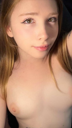 Woman with long light brown hair taking a close-up selfie.