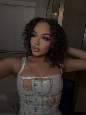 Woman with curly hair in floral corset top, posing indoors.