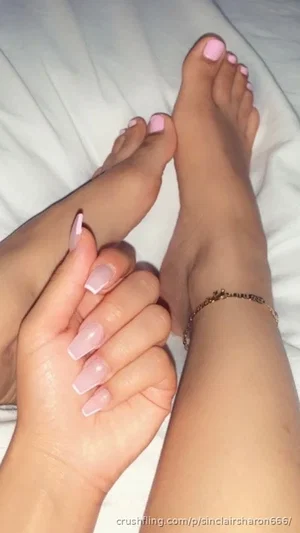 Close-up of feet and hand with pink nails, ankle bracelet, on white bedding.