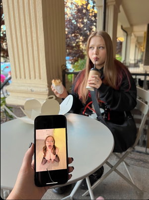 Woman with long hair sipping drink at outdoor cafe table.