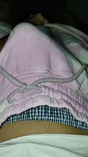 Person wearing pink sweatpants and checkered underwear, midsection visible, indoor setting.
