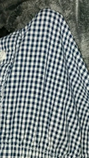 Close-up of blue and white checkered shirt fabric on a gray surface.