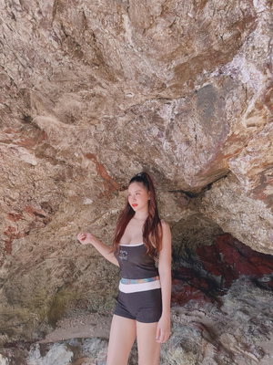 Woman with long hair in dark top and shorts at rocky shore.
