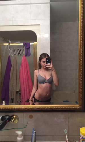 Woman in gray bra and panties in bathroom mirror selfie.
