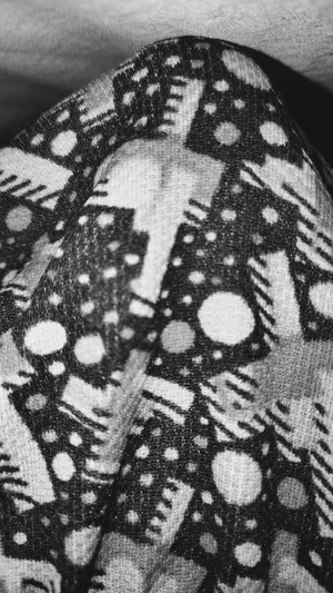 Close-up of patterned fabric, possibly clothing or blanket, in black and white.