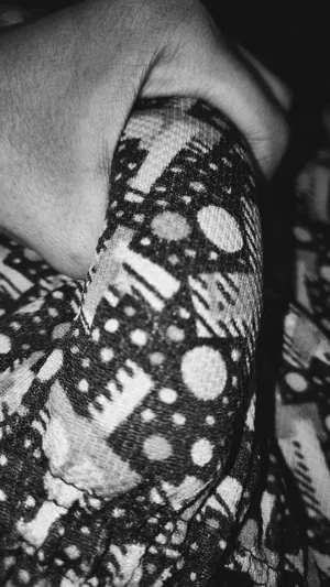 Close-up of hand gripping patterned fabric, black and white photo.