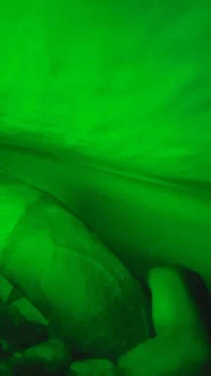 Green-tinted image showing indistinct body parts, possibly legs or torso, in low visibility.