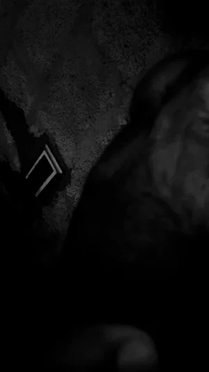 Dark, blurry image of a person's body part, possibly leg or torso, in dim lighting.