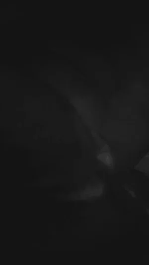 Dark, blurry image with indistinct shapes, no clear person or setting visible.