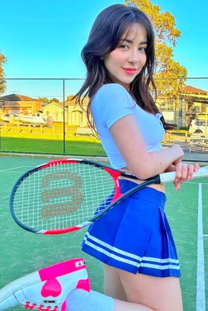 Woman in blue tennis outfit holding racket on outdoor court.