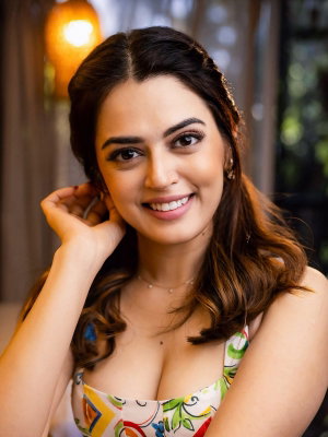 Smiling woman with long dark hair in colorful top indoors.