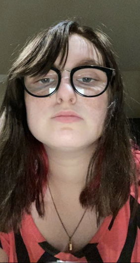 Woman with glasses and dark hair wearing a striped shirt indoors.