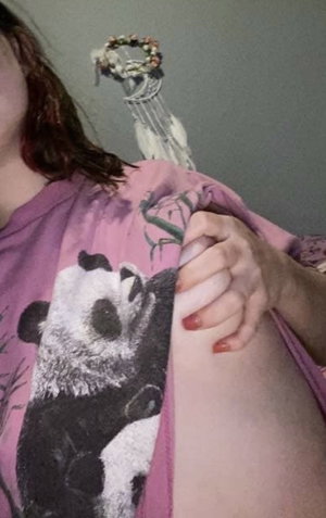 Woman in pink panda shirt exposing shoulder indoors.