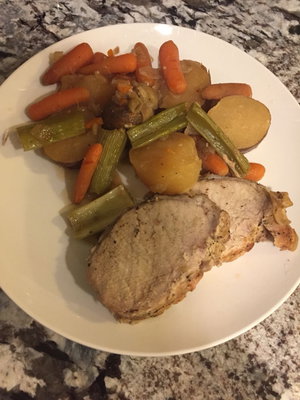 Plate of sliced pork with carrots, potatoes, and green beans on granite countertop.