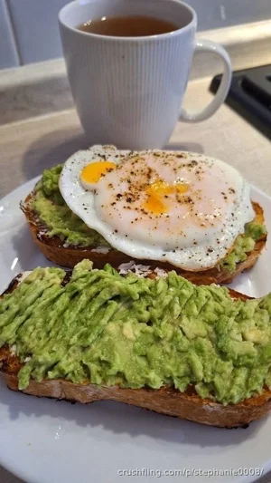 Avocado toast with fried egg and tea on a kitchen counter.