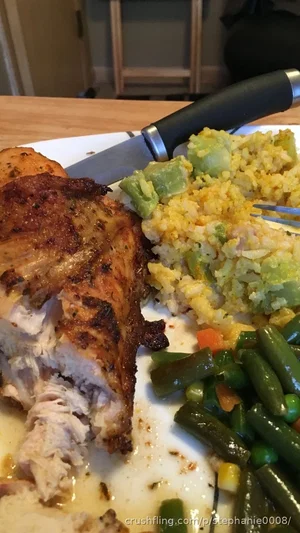 Plate of roasted chicken, yellow rice with vegetables, and green beans on a wooden table.