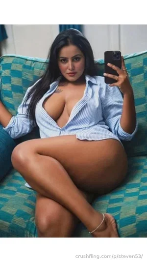 Woman with long dark hair in a blue striped shirt sitting on a checkered couch taking a mirror