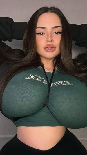 Woman with long dark hair wearing green zip-up top indoors.