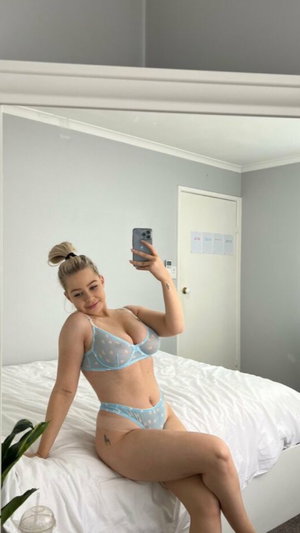 Blonde woman in blue lingerie on bed.