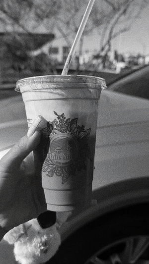 Hand with long nails holds drink cup in car.