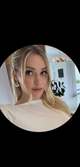 Blonde woman in white top taking indoor selfie.