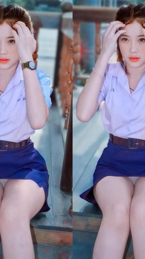 Asian woman in school uniform sitting with hand on head.