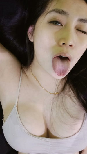 Woman with dark hair in tank top sticking out tongue in selfie.
