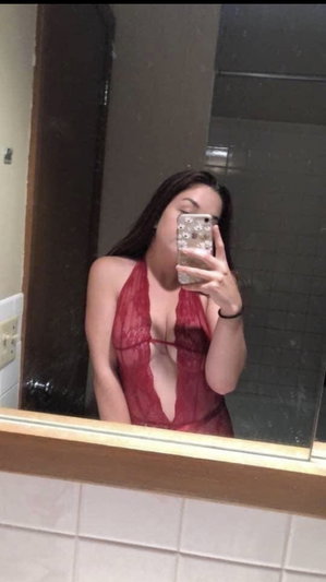 Woman in red lingerie taking mirror selfie in bathroom.