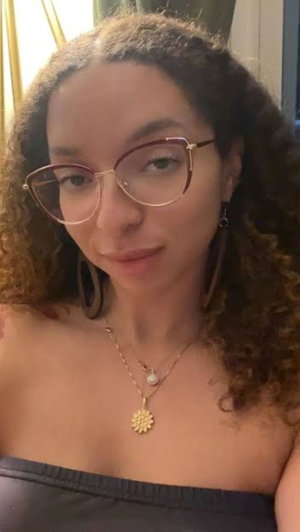 Woman with curly hair and glasses wearing black top.