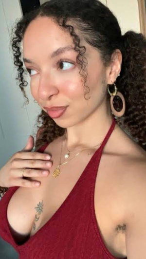Curly-haired woman in red halter top posing indoors.