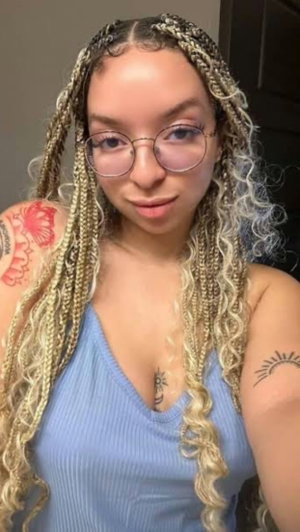 Woman with blonde braids and glasses in blue top taking selfie.