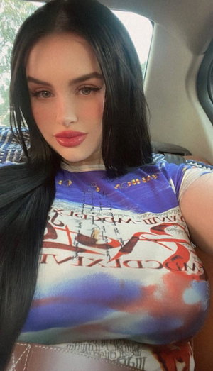 Brunette woman in colorful top in car.