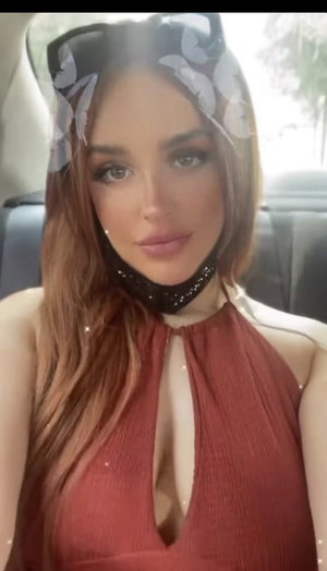 Woman with long brown hair in red halter top inside car