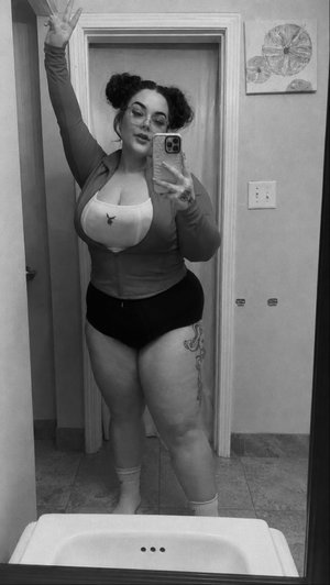 Woman in black underwear and long-sleeve top takes mirror selfie in bathroom.