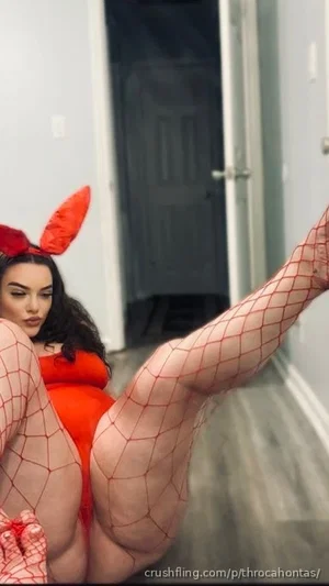 Woman in red devil costume with fishnet stockings posing indoors.