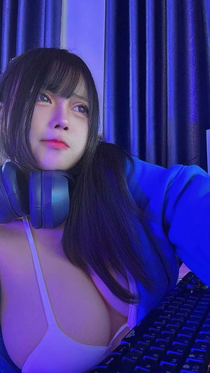 Dark-haired woman in white top with headphones indoors.