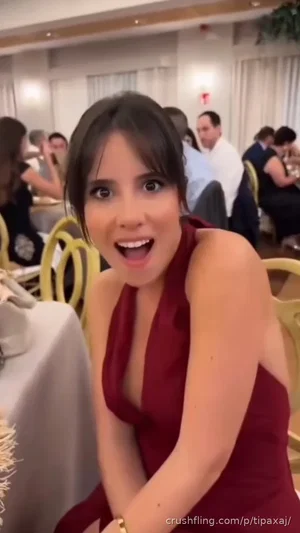 Woman in red dress smiling at camera in restaurant setting.