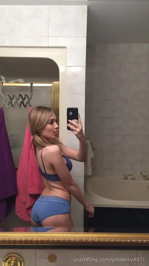 Woman in blue lingerie taking mirror selfie in bathroom.