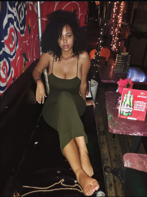 Curvy woman in green dress sitting indoors at a bar.