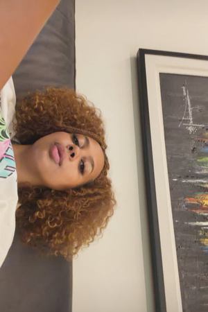 Woman with curly hair in white t-shirt indoors.