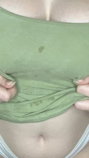 Woman lifting green top to reveal midriff.